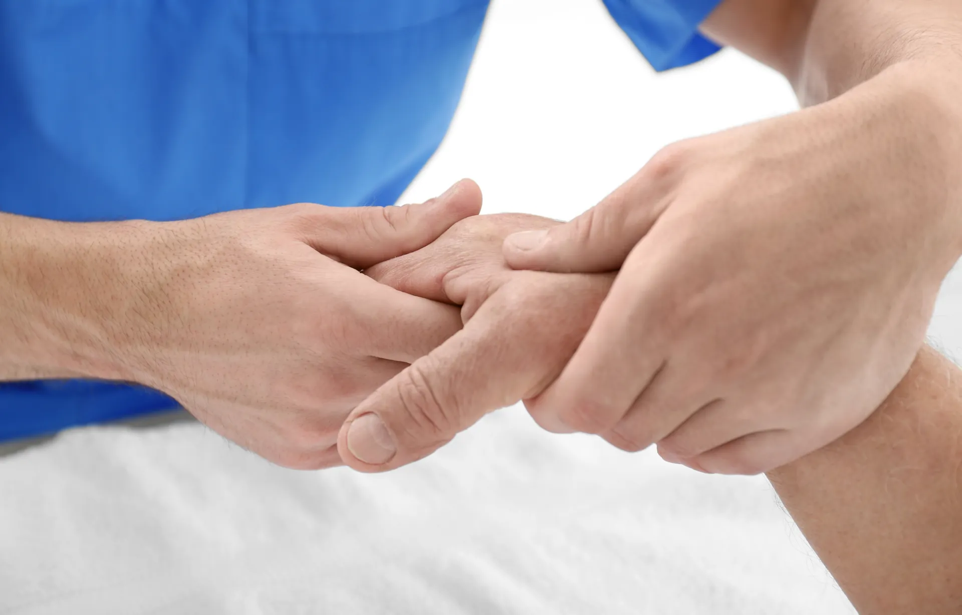 Therapeutin untersucht und mobilisiert die Finger einer Patientin