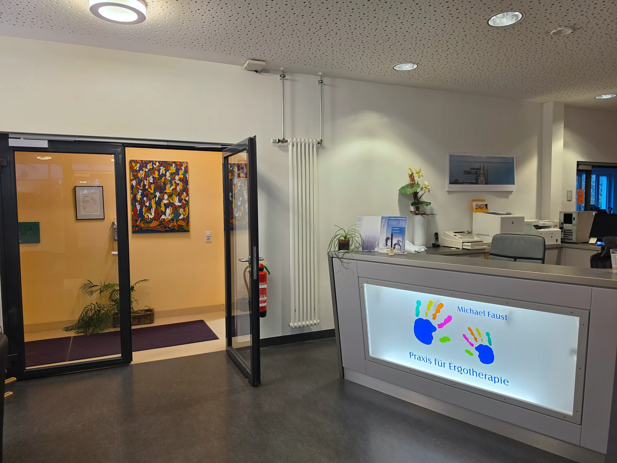 Empfangsbereich der Praxis mit Blick in den Flur und Kunstwerken